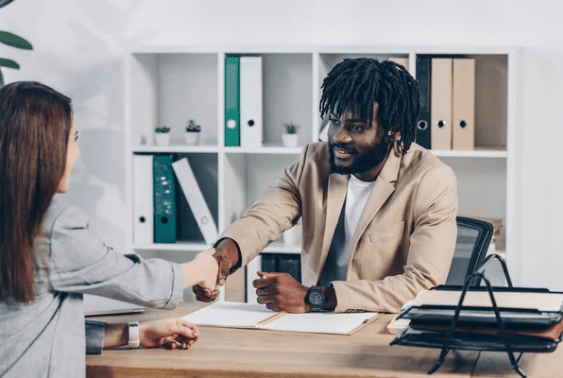 A smiling job seeker shakes hands with his new employer